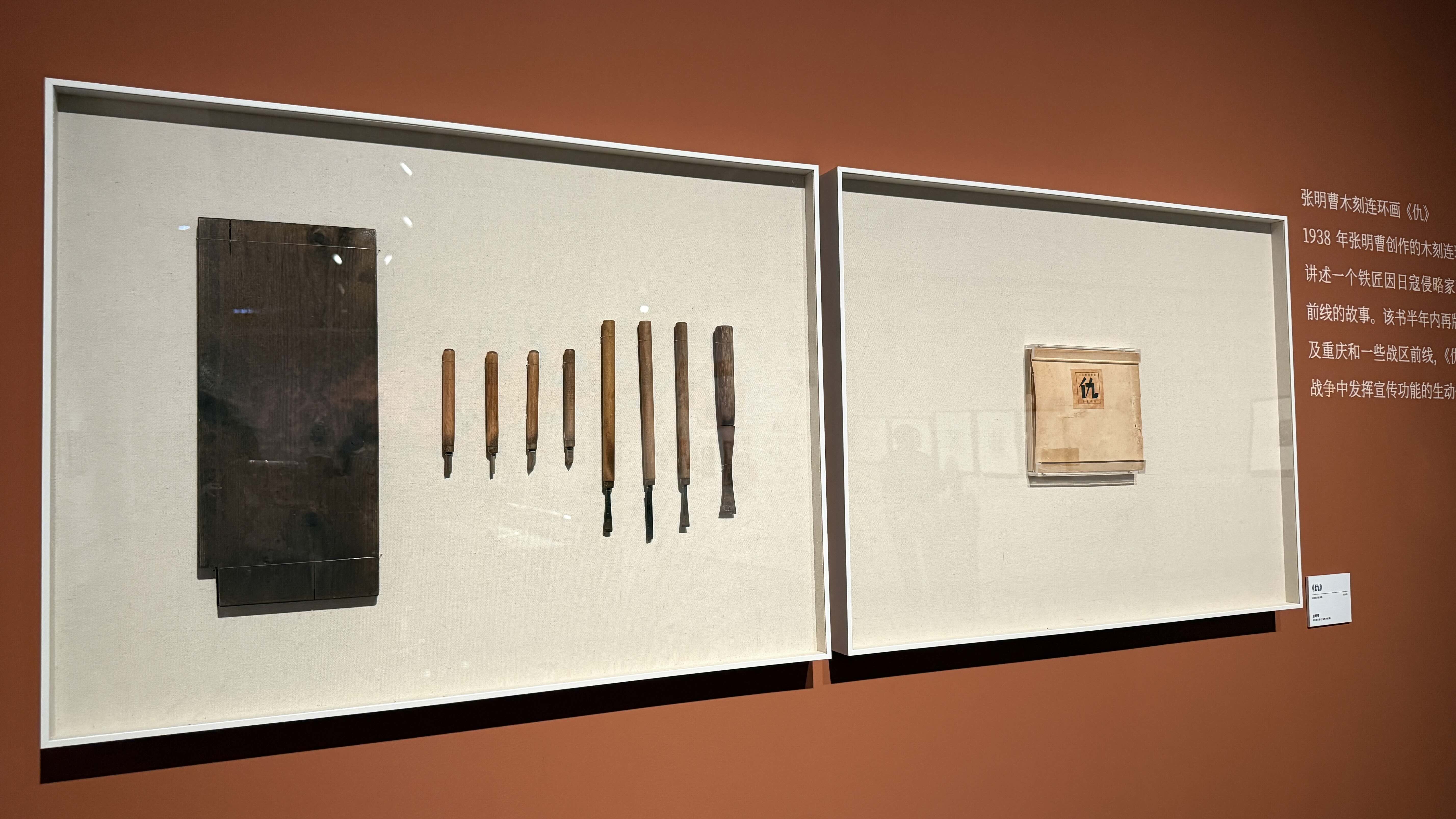 Un morceau de vieux bois et des outils de sculpture sont affichés dans l'exposition, à côté d'un livre intitulé