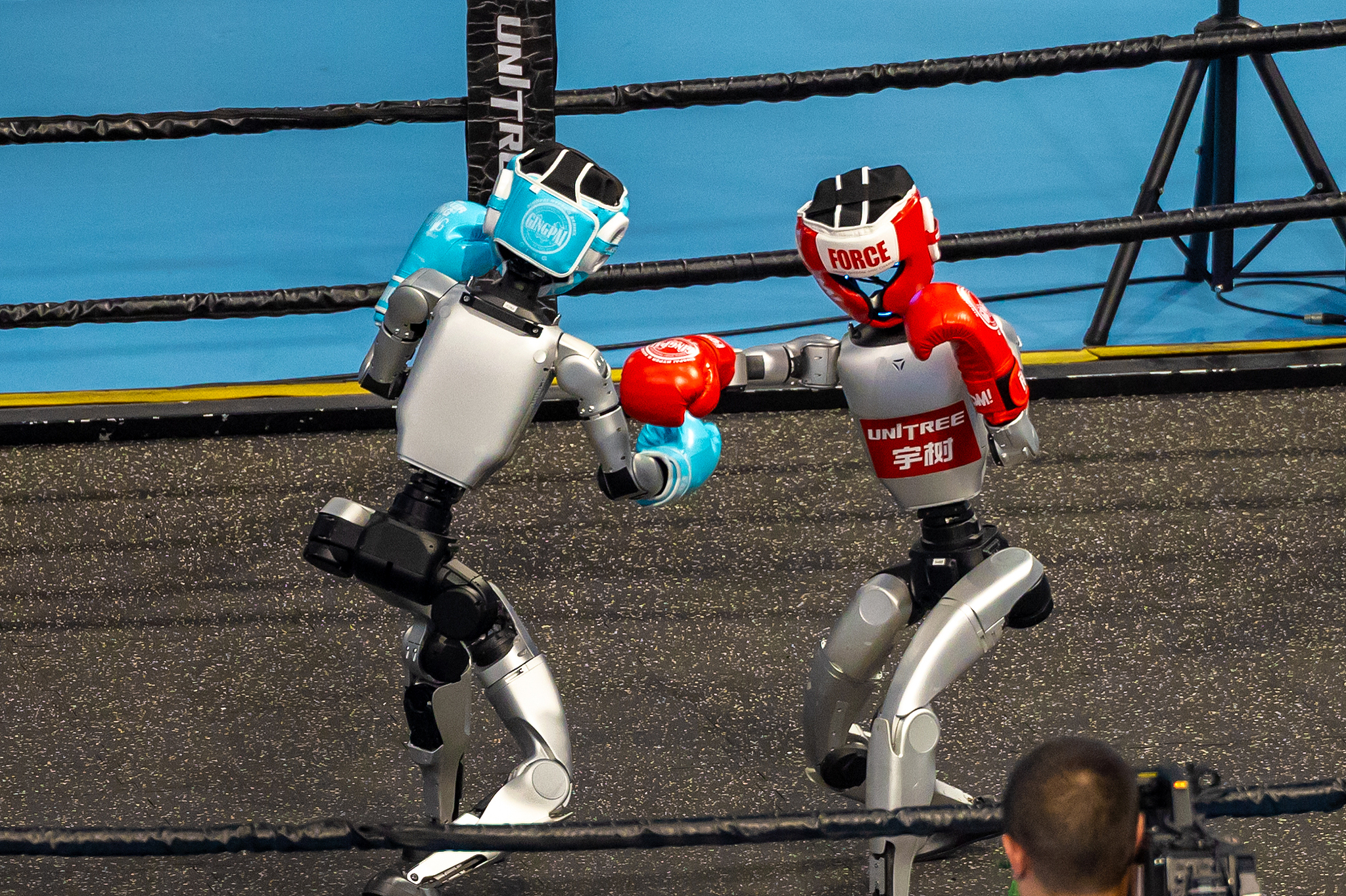 Deux robots humanoïdes s'affrontent dans une démonstration de kickboxing lors de la cérémonie d'ouverture des jeux de robot humanoïde mondial 2025 à Pékin, 14 août 2025. / VCG