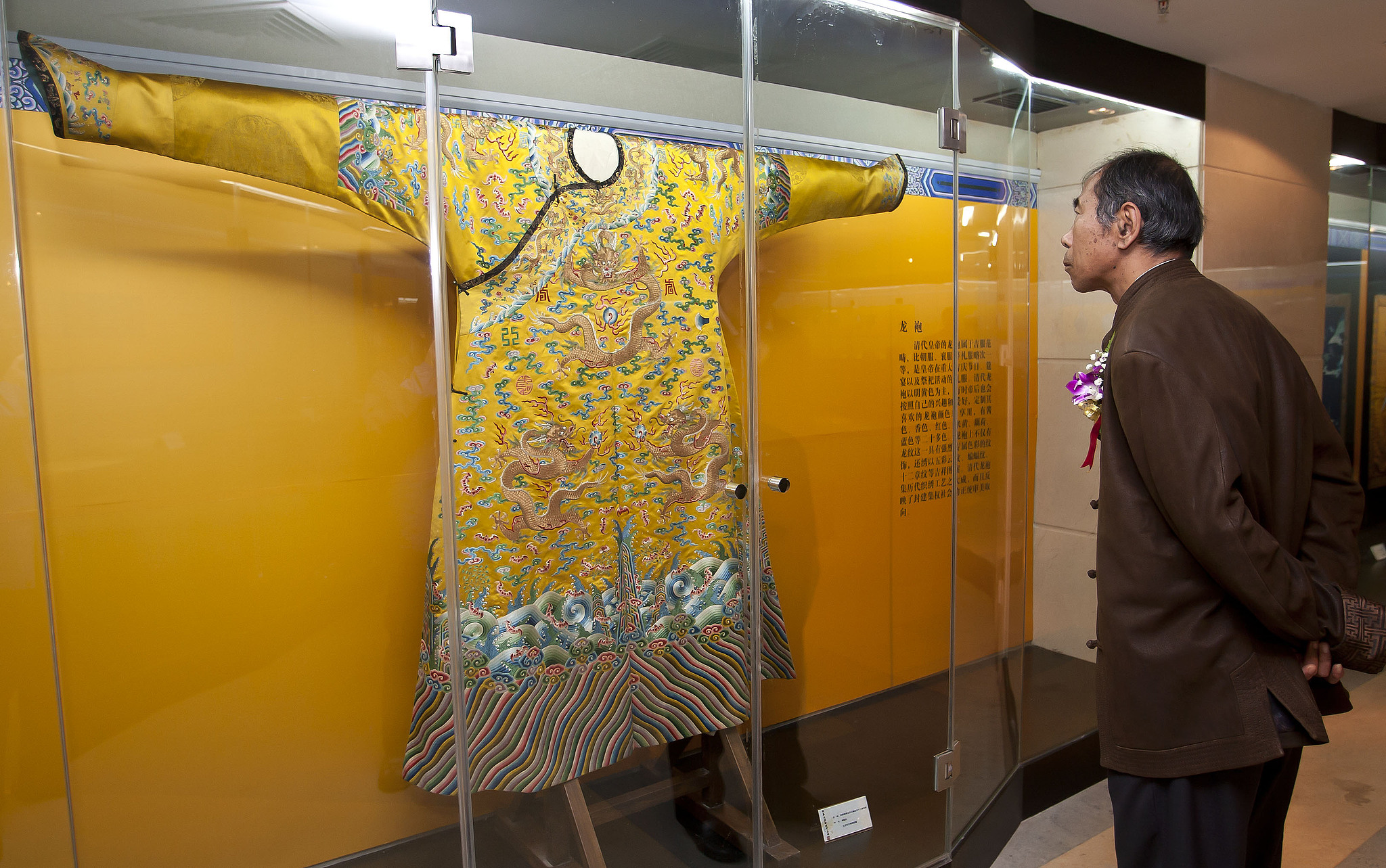 Une photo d'archive montre un homme admirant la robe de dragon des empereurs de la dynastie Qing lors d'une exposition à Pékin. /VCG 