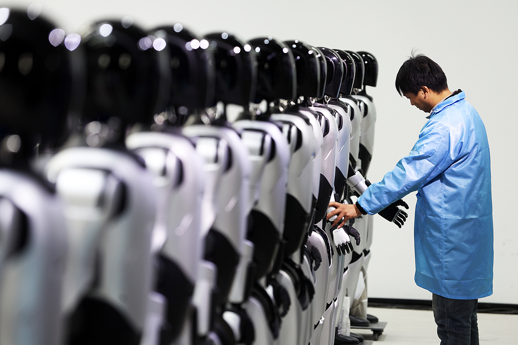 Un ingénieur ajuste des robots dans une usine de production de masse, dans la municipalité de Shanghai, dans l'est de la Chine, le 8 décembre 2025. /VCG