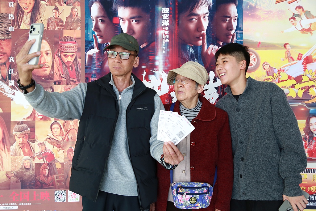 Trois générations d'une famille prennent un selfie devant des affiches de films dans un cinéma de Mengzi, province du Yunnan, le 17 février 2026. /VCG
