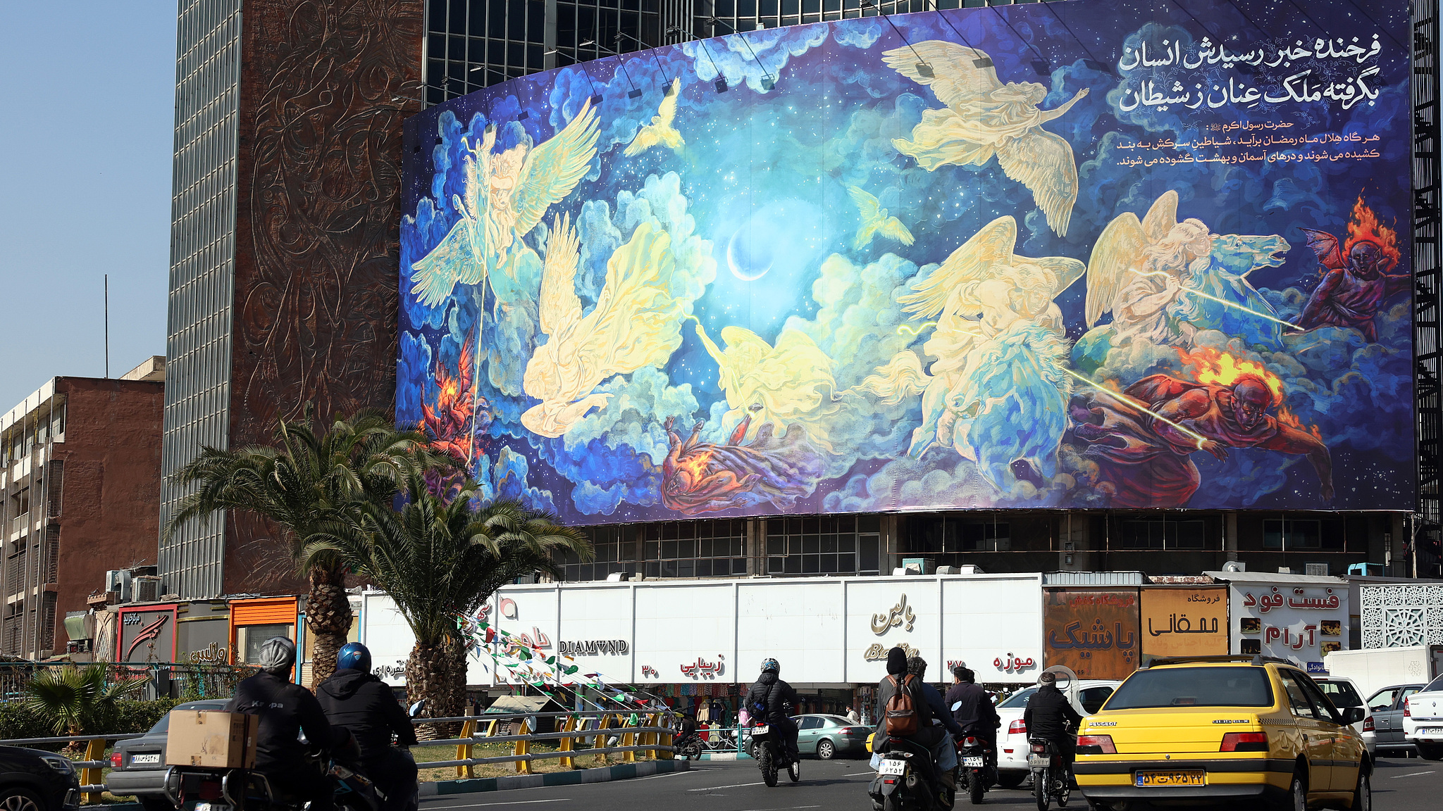 Des Iraniens passent devant un immense panneau publicitaire sur lequel est écrit un poème persan