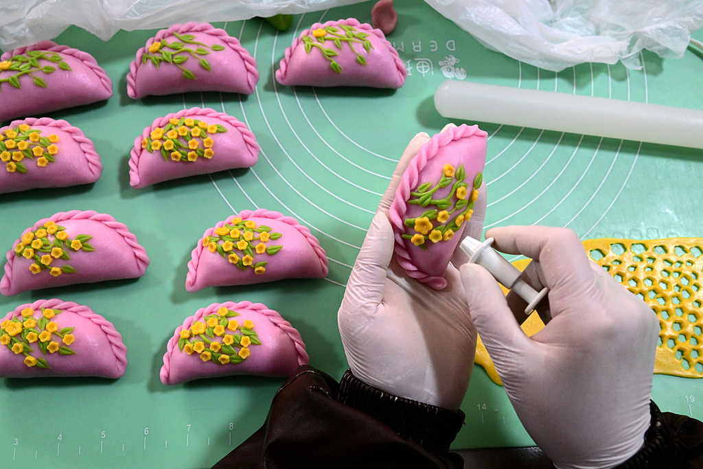 Un fabricant de boulettes façonne de délicats motifs floraux sur Qingming Guo dans l'atelier de Wang Lijuan à Jinhua, province du Zhejiang, Chine. /VCG