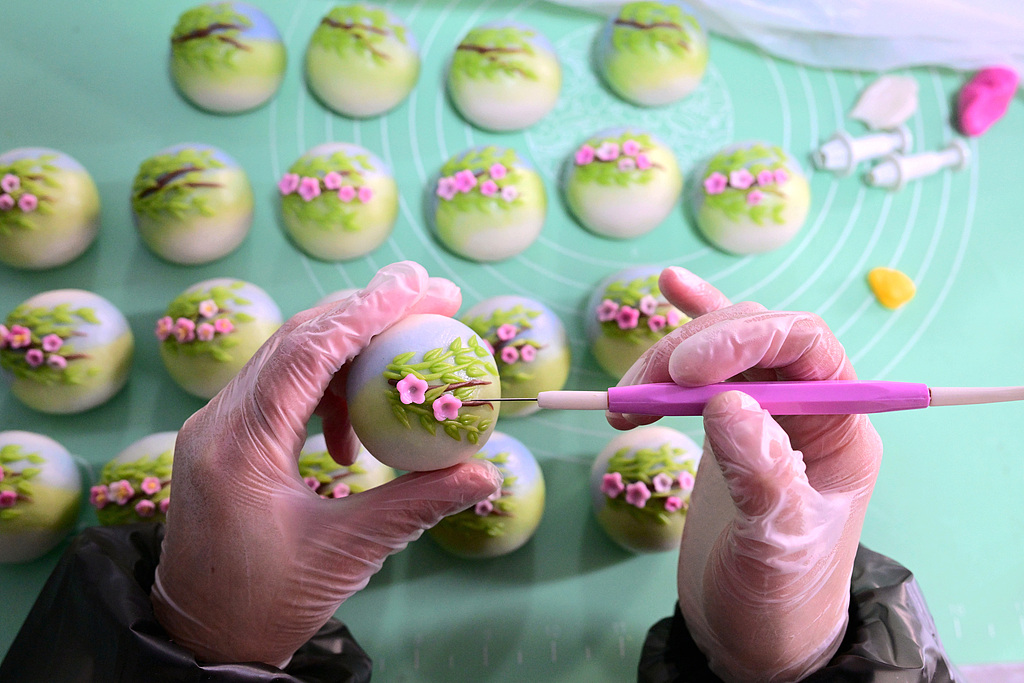 Un fabricant de boulettes façonne de délicats motifs floraux sur Qingming Guo dans l'atelier de Wang Lijuan à Jinhua, province du Zhejiang, Chine. /VCG