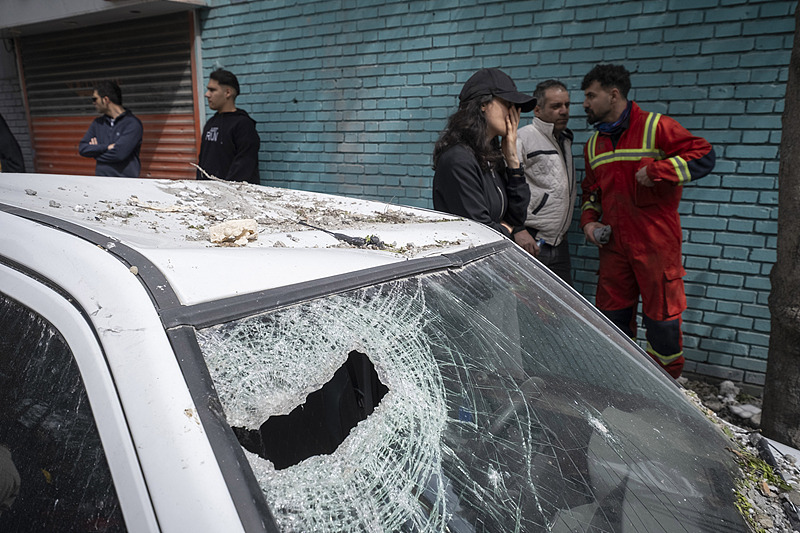 Un membre de l'équipe de secours et des habitants se tiennent derrière un véhicule détruit lors d'une frappe aérienne contre un immeuble résidentiel à Téhéran, en Iran, le 27 mars 2026. /Xinhua
