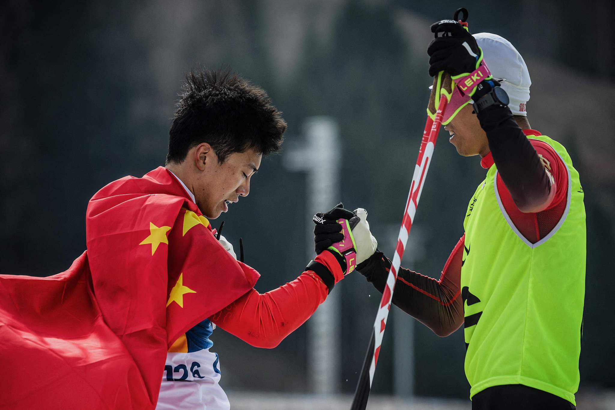 Le Chinois Yu Shuang (à gauche) et son guide Shang Jincai célèbrent leur victoire dans la poursuite de sprint en biathlon masculin lors des Jeux paralympiques d'hiver de Milan Cortina à Tesero, en Italie, le 13 mars 2026. /VCG