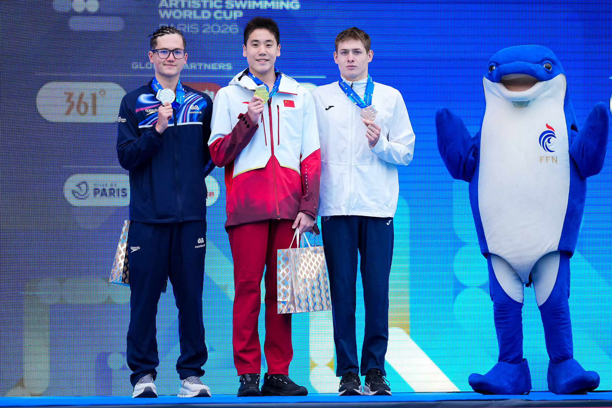 De gauche à droite : Le médaillé d'argent Ranjuo Tomblin de Grande-Bretagne, le médaillé d'or Guo Muye de Chine et le médaillé de bronze Viktor Druzin du Kazakhstan affichent leurs récompenses après la finale technique solo masculine à la Coupe du monde de natation artistique à Paris, France, le 27 mars 2026. /VCG