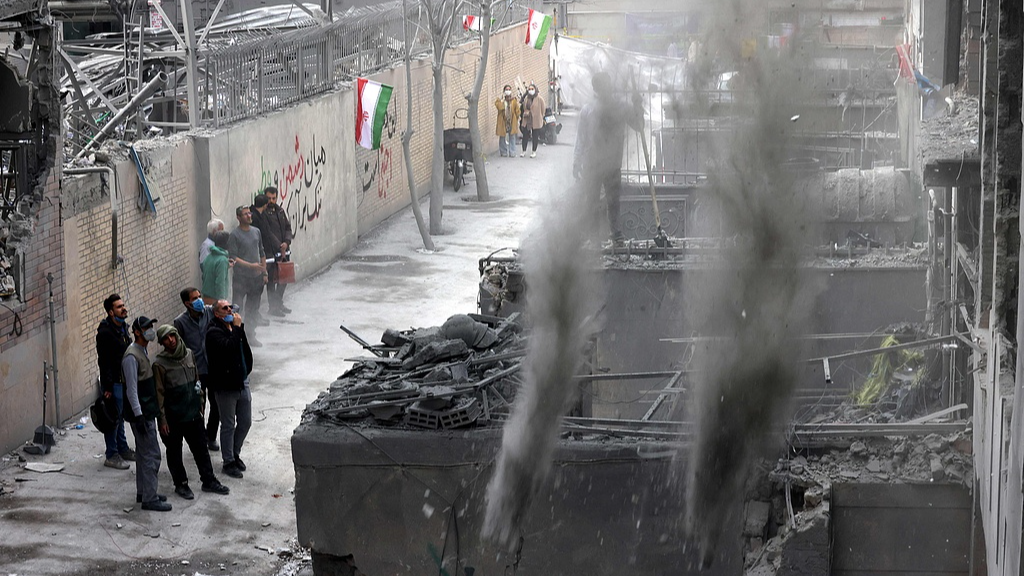 Des résidents iraniens regardent le nettoyage des débris d'un bâtiment endommagé à Téhéran, capitale de l'Iran, le 15 mars 2026. /VCG