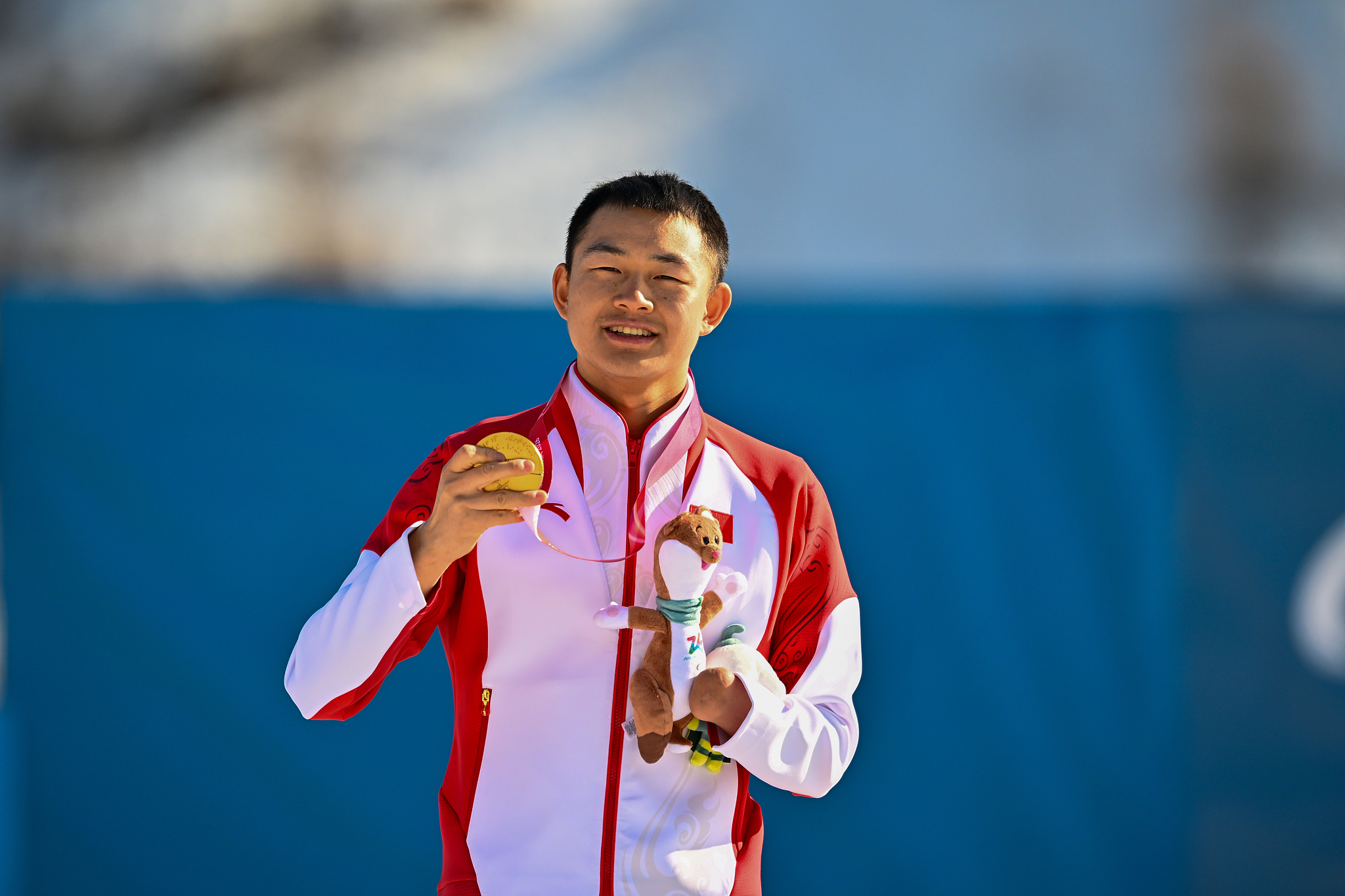Le médaillé d'or chinois Cai Jiayun montre sa médaille d'or après avoir remporté la finale debout du sprint de biathlon masculin aux Jeux paralympiques d'hiver de Milan Cortina 2026 à Val di Fiemme, en Italie, le 7 mars 2026. /VCG