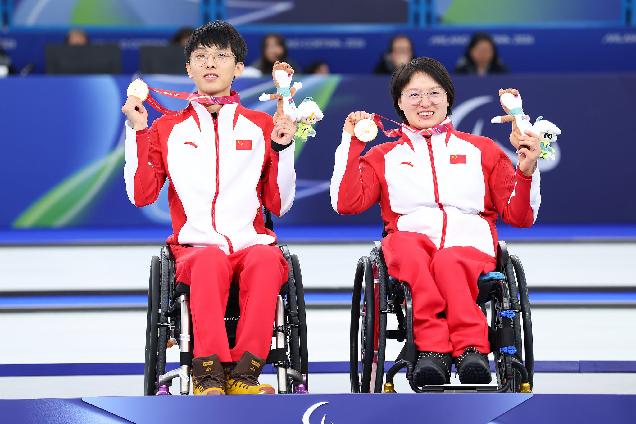 Les médaillés d'or Yang Jinqiao (à gauche) et Wang Meng présentent leurs récompenses après avoir remporté la finale de curling en fauteuil roulant en double mixte aux Jeux paralympiques d'hiver de Milan Cortina 2026 à Cortina d'Ampezzo, en Italie, le 11 mars 2026. /VCG