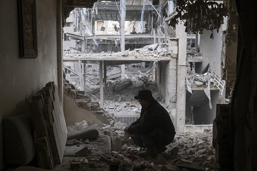 Un homme cherche ses affaires parmi les ruines de son appartement près d'un commissariat de police dans un quartier résidentiel de Téhéran, Iran, le 15 mars 2026. /VCG