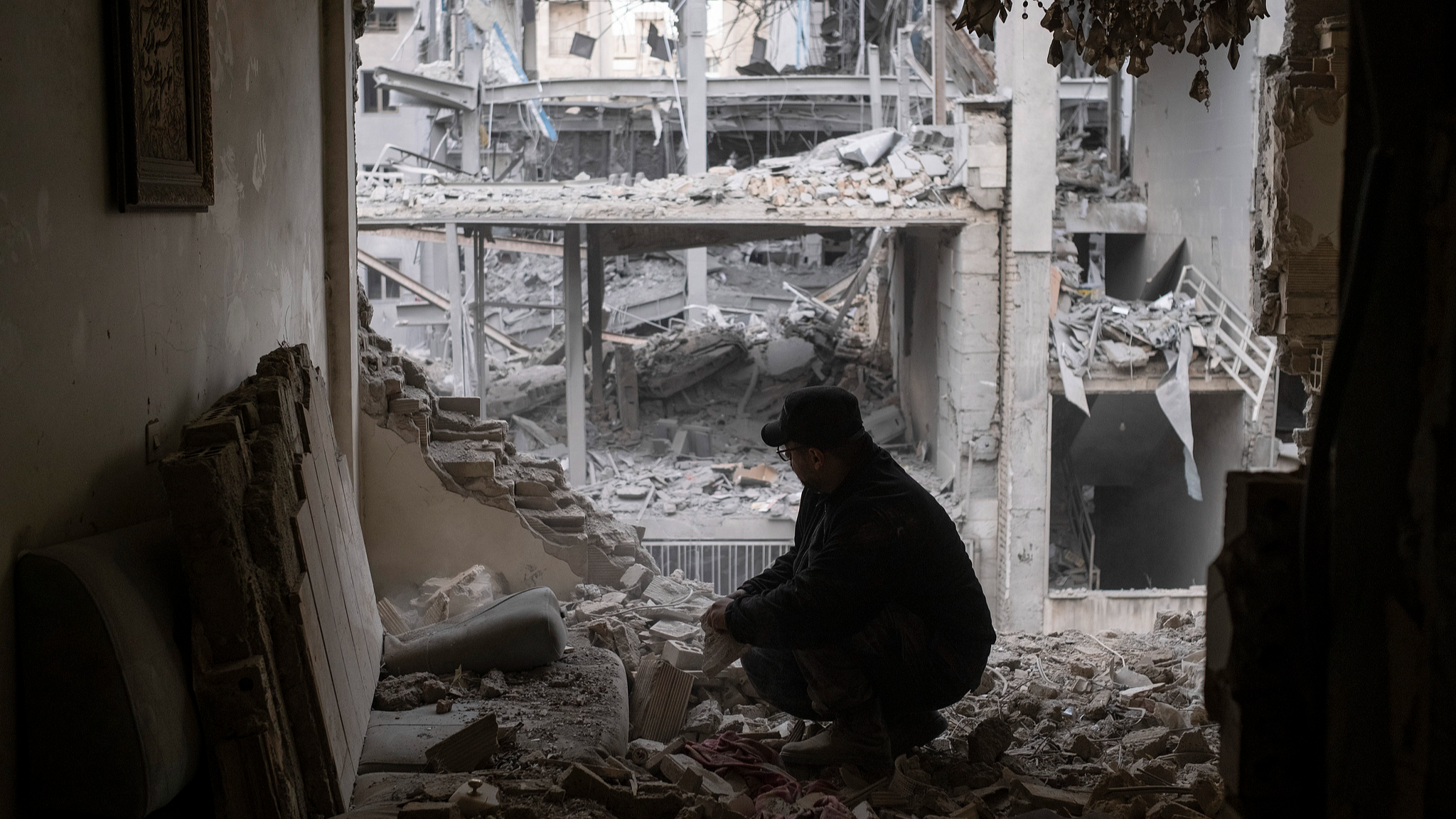 Un homme cherche ses affaires parmi les ruines de son appartement près d'un commissariat de police dans un quartier résidentiel de Téhéran, Iran, le 15 mars 2026. /VCG