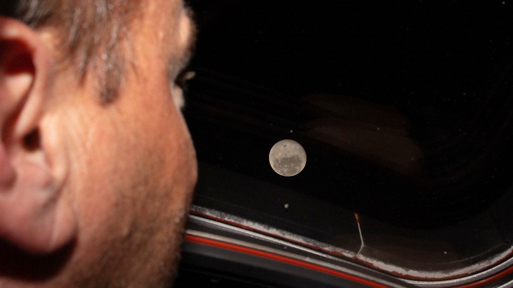 Le commandant d'Artemis II et astronaute de la NASA, Reid Wiseman, regarde l'une des principales fenêtres de la cabine du vaisseau spatial Orion sur la lune avant le survol lunaire de l'équipage, le 6 avril 2026. /VCG