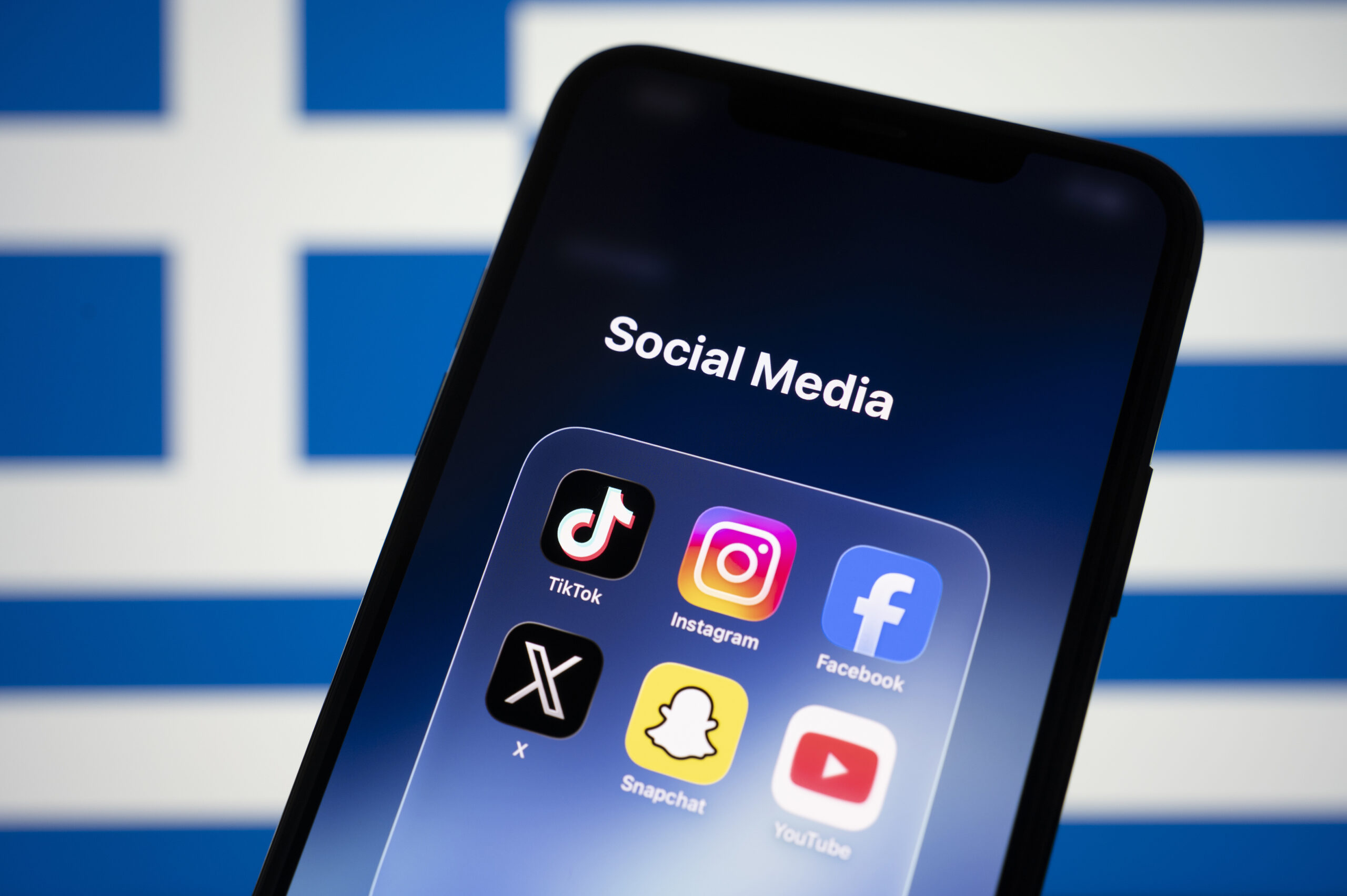 Un smartphone affiche les logos des réseaux sociaux avec un drapeau grec en arrière-plan. /VCG