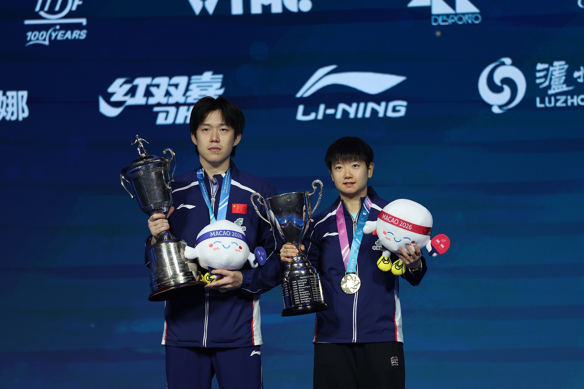 Les Chinois Wang Chuqin (à gauche) et Sun Yingsha affichent leurs trophées respectifs des championnats masculin et féminin lors de la cérémonie de remise des prix lors de la Coupe du monde masculine et féminine de l'ITTF dans la RAS chinoise de Macao (région administrative spéciale), le 5 avril 2026. /VCG