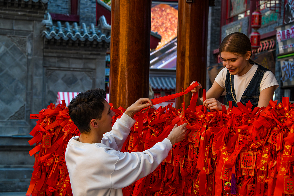 Deux étudiants internationaux russes participent à un rituel de bénédiction traditionnel sur un site pittoresque de Shenyang, province du Liaoning, le 11 mai 2025. /VCG
