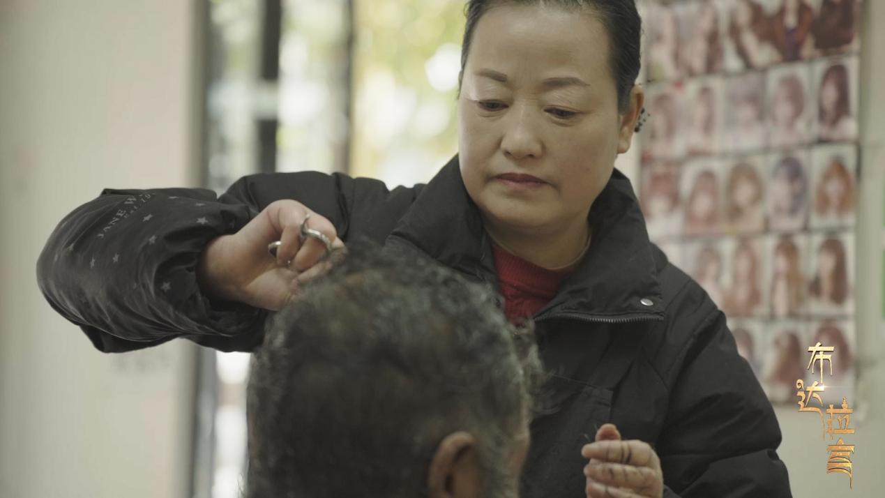 Yao Xiaoying, propriétaire d'un salon de coiffure, coupe les cheveux d'un résident de la communauté de Xigaze, Xizang en Chine. /CGTN