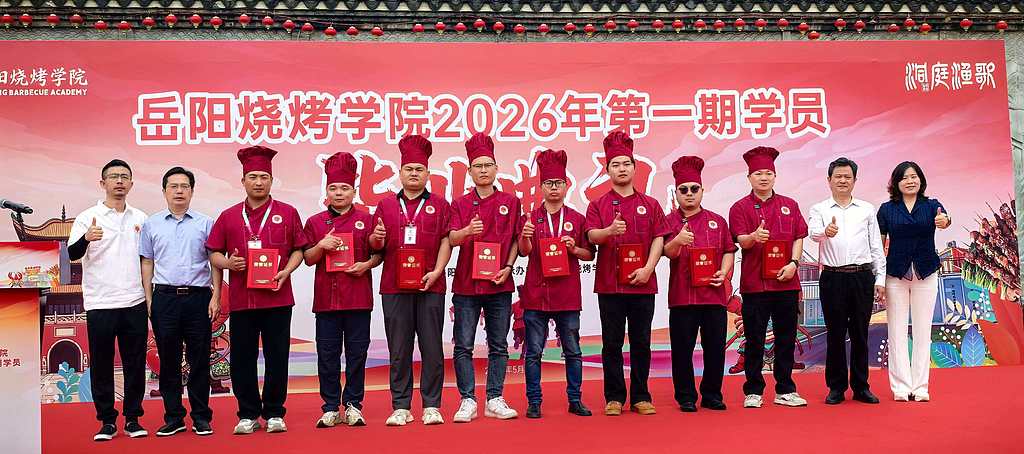 Le premier groupe de diplômés de l'Académie de barbecue de Yueyang pose pour une photo dans la province du Hunan le 20 mai 2026. /VCG