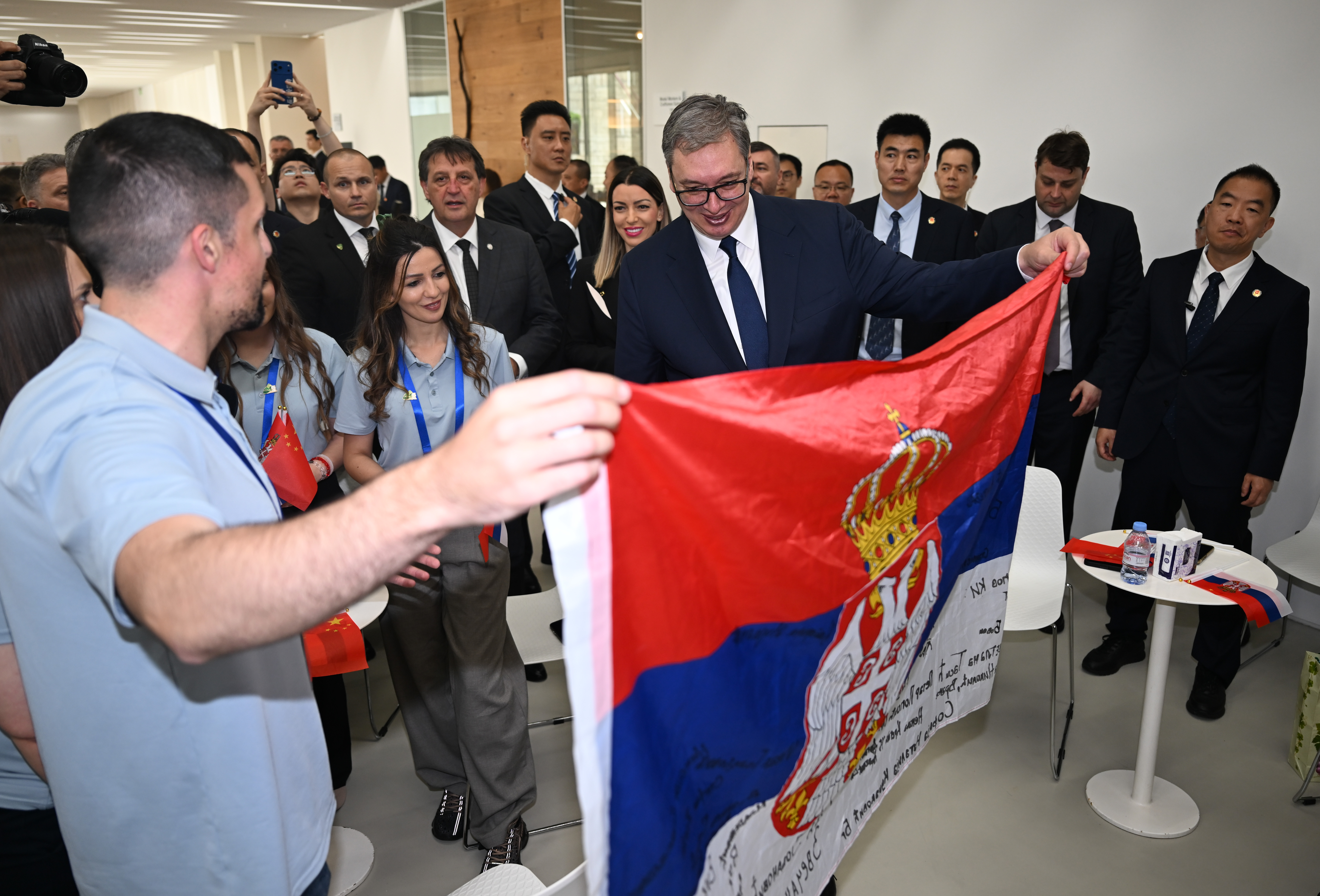 De jeunes Serbes participant à un programme d'échange en Chine présentent un drapeau serbe signé de leur nom au président serbe Aleksandar Vucic au groupe Minth à Jiaxing, dans la province chinoise du Zhejiang (est), le 27 mai 2026. /IC