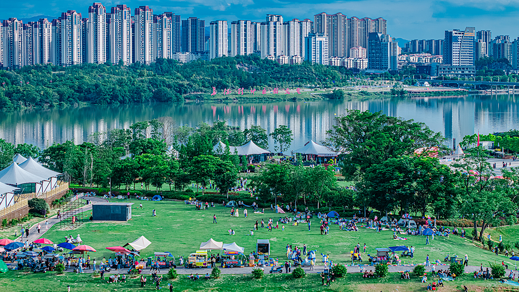 Des foules de visiteurs remplissent un parc urbain, où les arbres luxuriants et les eaux claires se mélangent harmonieusement aux bâtiments urbains, ville de Ganzhou, province du Jiangxi (est de la Chine), le 1er mai 2026. /VCG