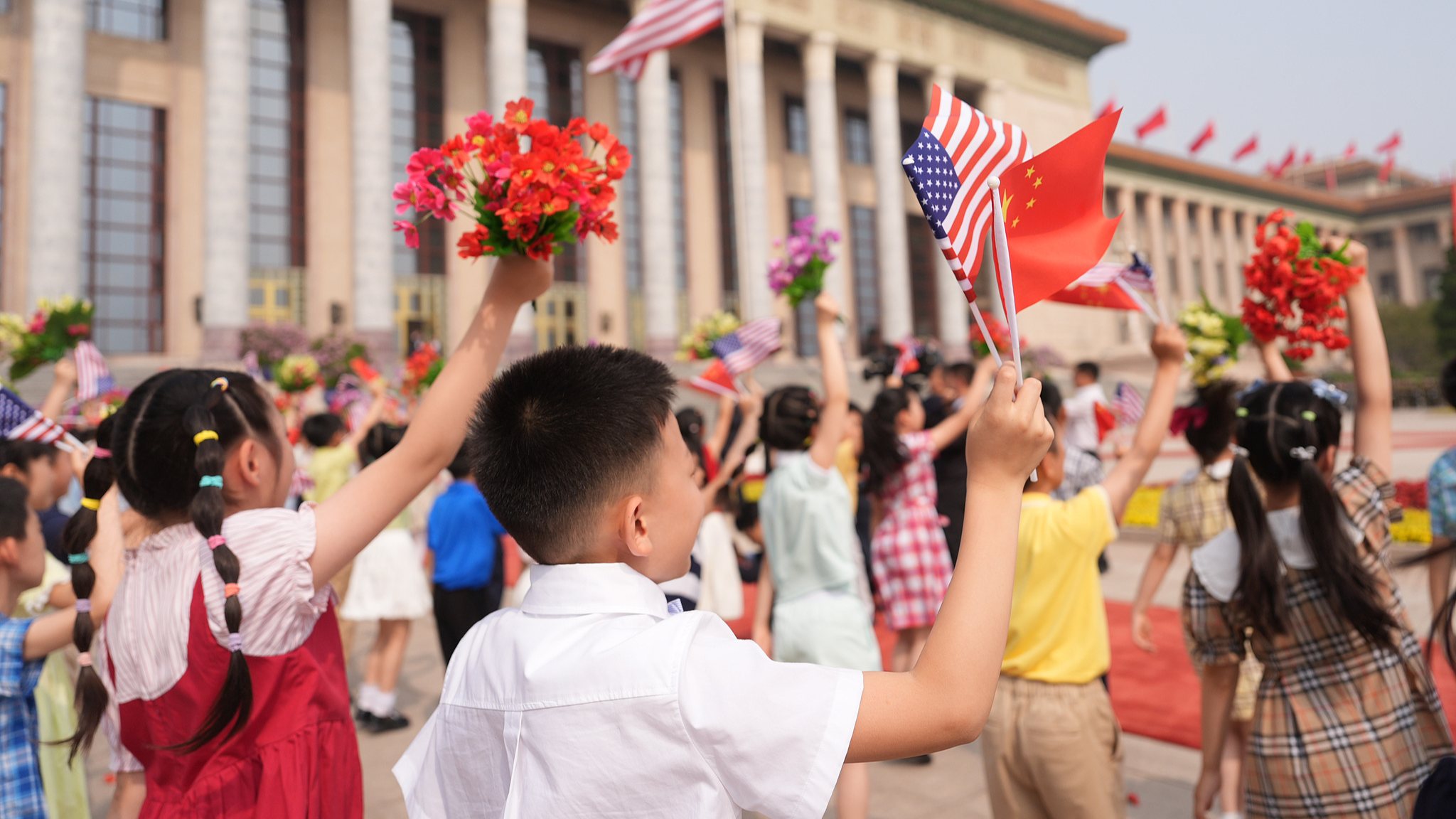 Des enfants brandissent des fleurs et des drapeaux chinois et américains au Grand Palais du Peuple à Pékin, en Chine, le 14 mai 2026. /VCG