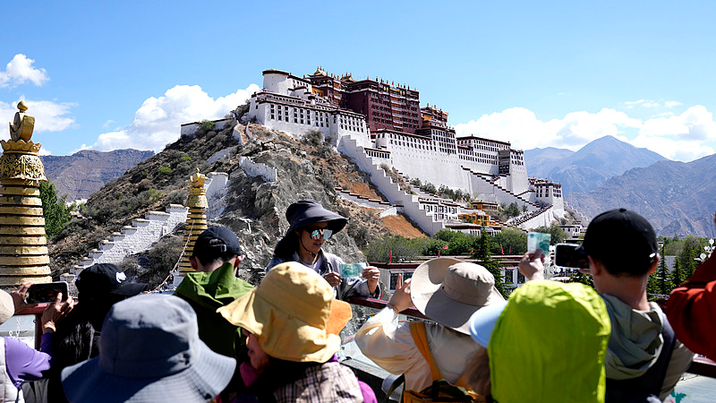 Des visiteurs prennent des photos avec le palais du Potala à Lhassa, dans la région autonome de Xizang (sud-ouest de la Chine), le 23 mai 2026, jour du 75e anniversaire de la libération pacifique de Xizang. /VCG