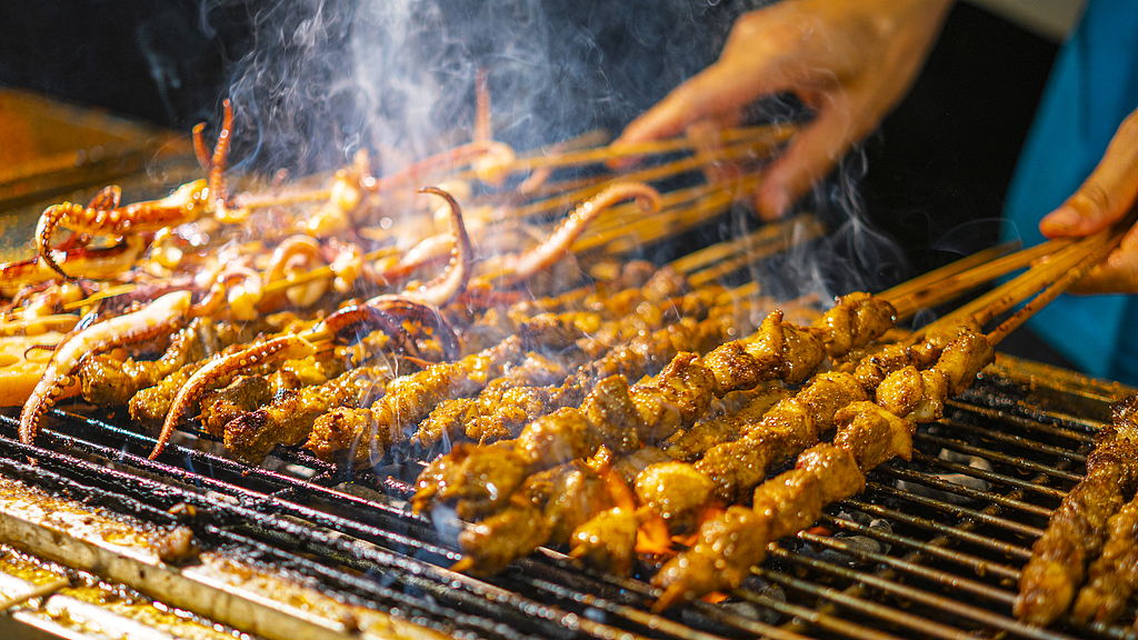 Un gros plan d'un chef faisant griller des brochettes. /VCG