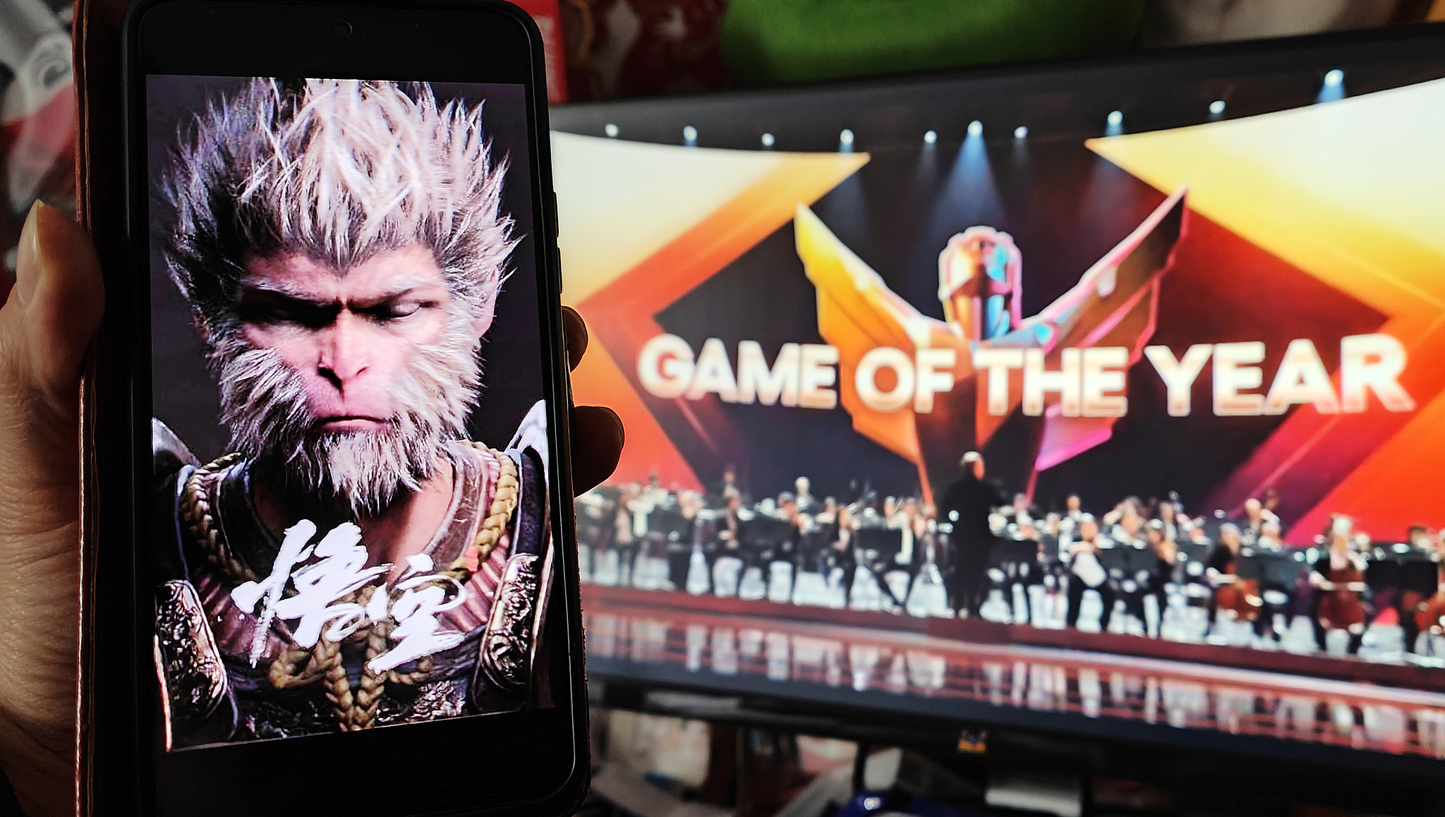 Un joueur à Shanghai tient un téléphone affichant une affiche de Black Myth : Wukong tout en regardant le jeu remporter le prix du jeu de l'année lors de la cérémonie des Game Awards (TGA) 2024 en décembre 2024. /VCG