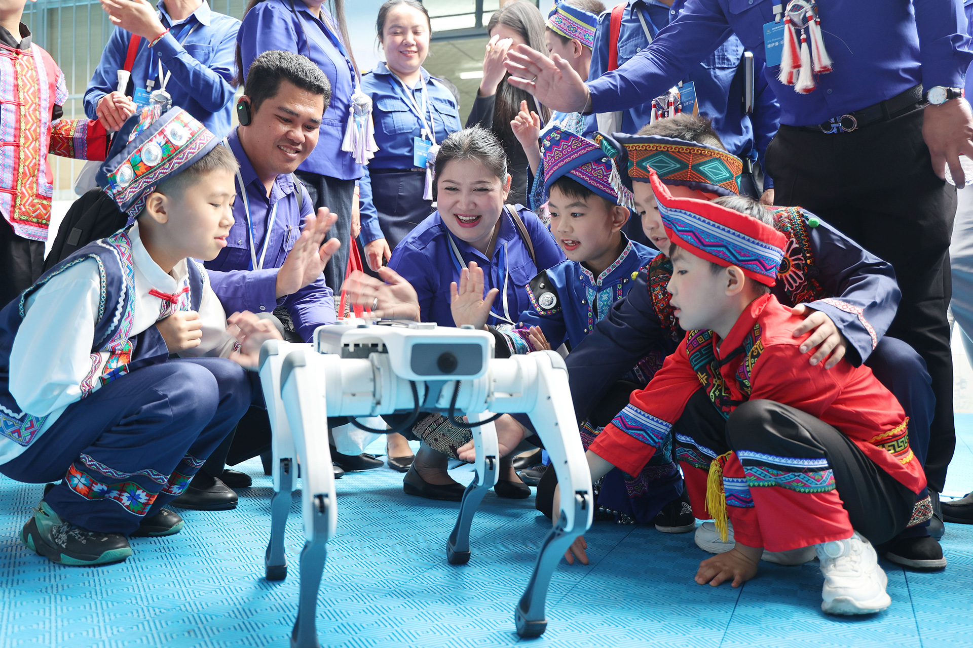 De jeunes représentants du Laos interagissent avec un chien robot lors d'une visite dans un centre de jeunesse à Nanning, dans la région autonome Zhuang du Guangxi, le 22 mars 2026. /IC