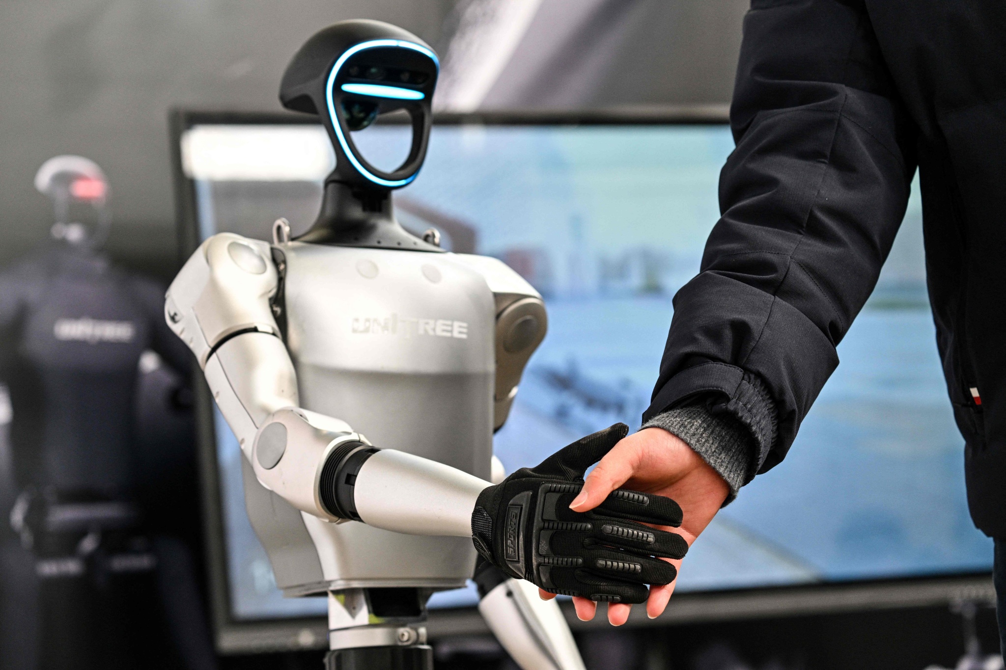 Un homme serre la main d'un robot humanoïde d'Unitree Robotics lors de la Global Developer Conference, organisée par la Shanghai AI Industry Association, à Shanghai, en Chine, le 21 février 2025. /VCG
