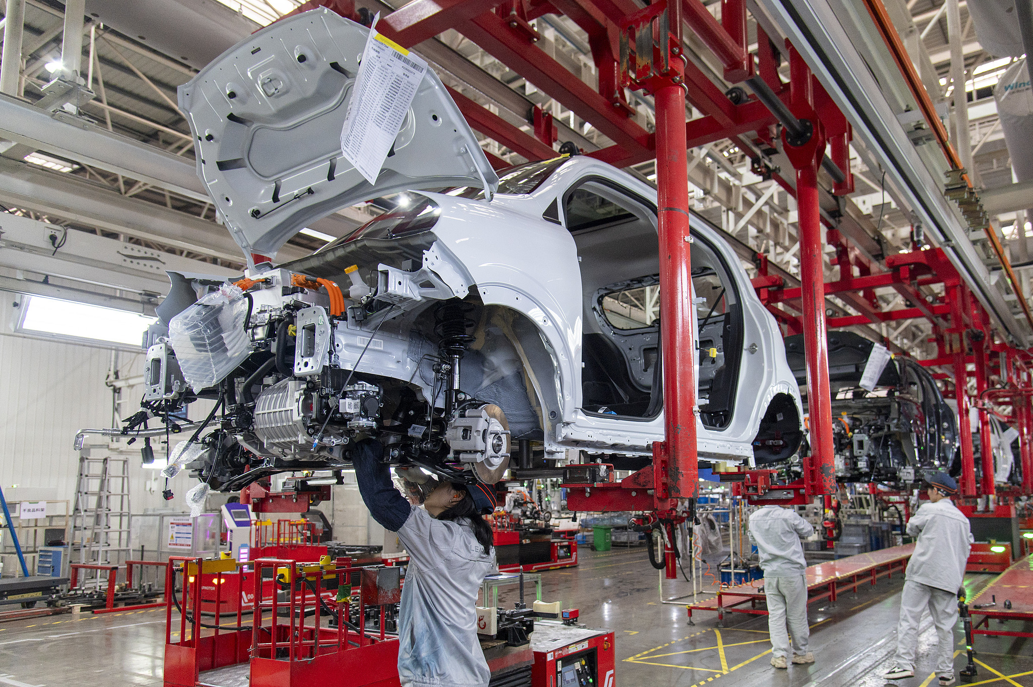 Des ouvriers installent des composants dans un véhicule électrique dans une usine de fabrication. /VCG