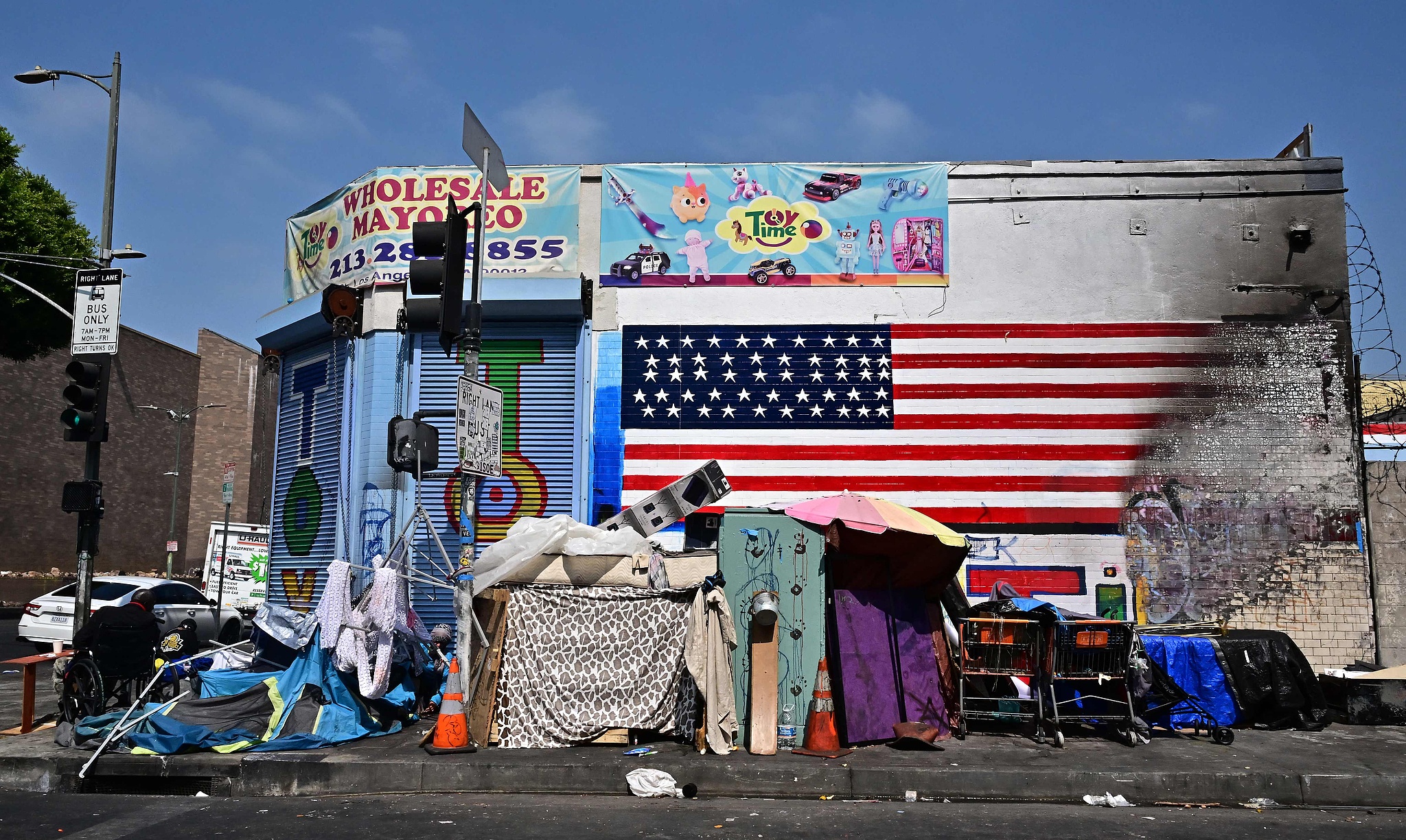 Le drapeau des États-Unis est partiellement détruit sur un mur derrière un campement de sans-abri à Los Angeles, en Californie, le 13 août 2025. /CFP
