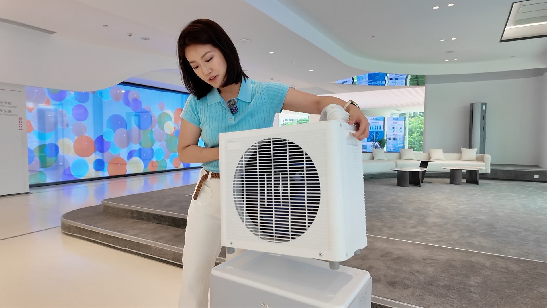 Un journaliste de CGTN soulève le condenseur extérieur d'un climatiseur mobile split, le 29 juin 2026. /CGTN
