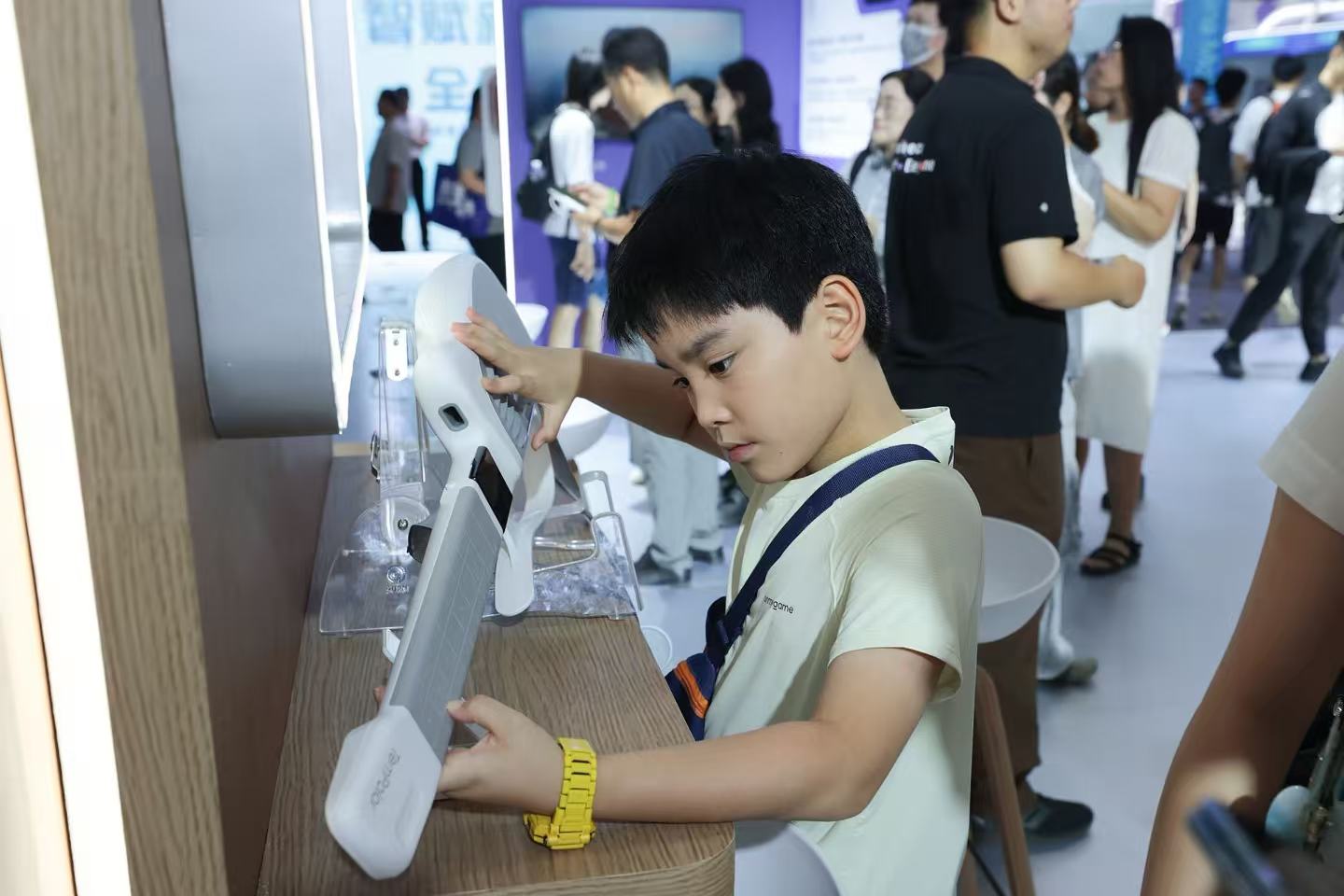 Un enfant fait l'expérience d'une guitare alimentée par l'IA lors de la Conférence mondiale sur l'intelligence artificielle 2026 à Shanghai, en Chine, le 20 juillet 2026. /VCG