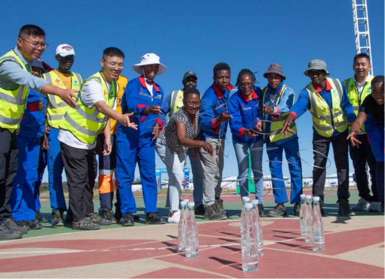Des employés chinois et namibiens participent à un jeu de lancer d'anneaux dans le camping de la phase III du projet routier de l'aéroport international Hosea Kutako, au sud-est de la capitale Windhoek, en Namibie, le 1er février 2026. /Xinhua
