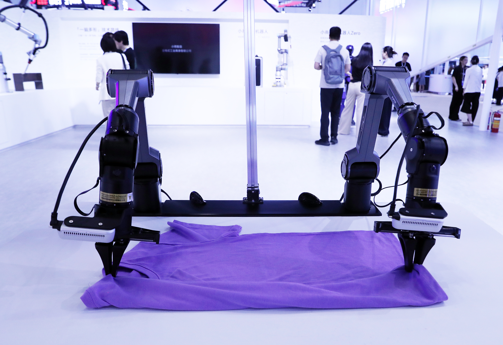 Les exposants présentent des robots pliant des vêtements à l'exposition 2026 de l'industrie de l'économie numérique à Pékin, en Chine, le 3 juillet 2026. /VCG