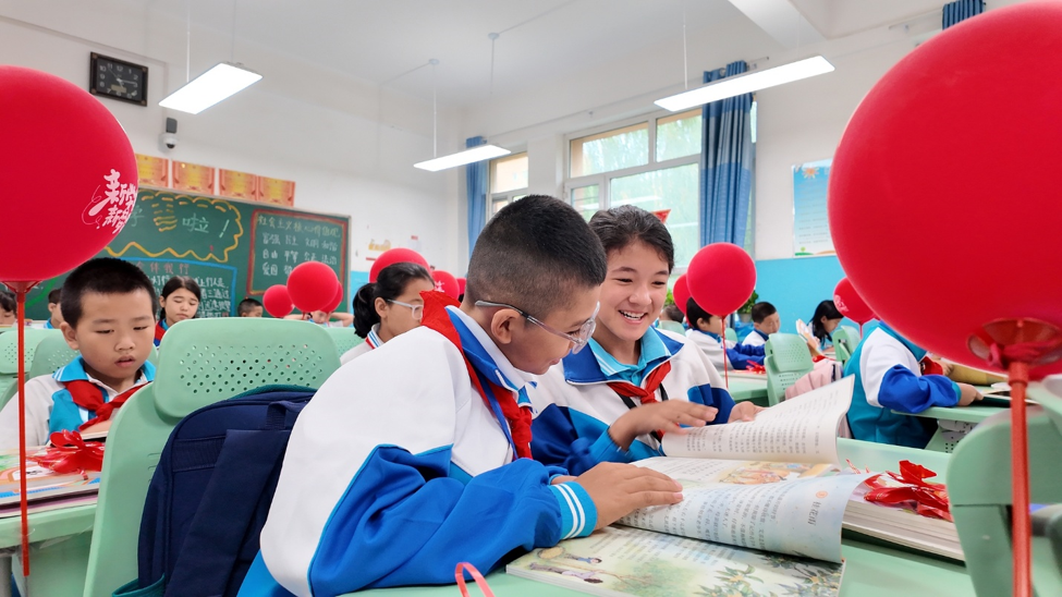 Des élèves vérifient leurs nouveaux manuels scolaires le premier jour d'un nouveau semestre dans une école primaire de la préfecture d'Aksu, région autonome ouïgoure du Xinjiang, nord-ouest de la Chine, le 24 août 2025. /CFP