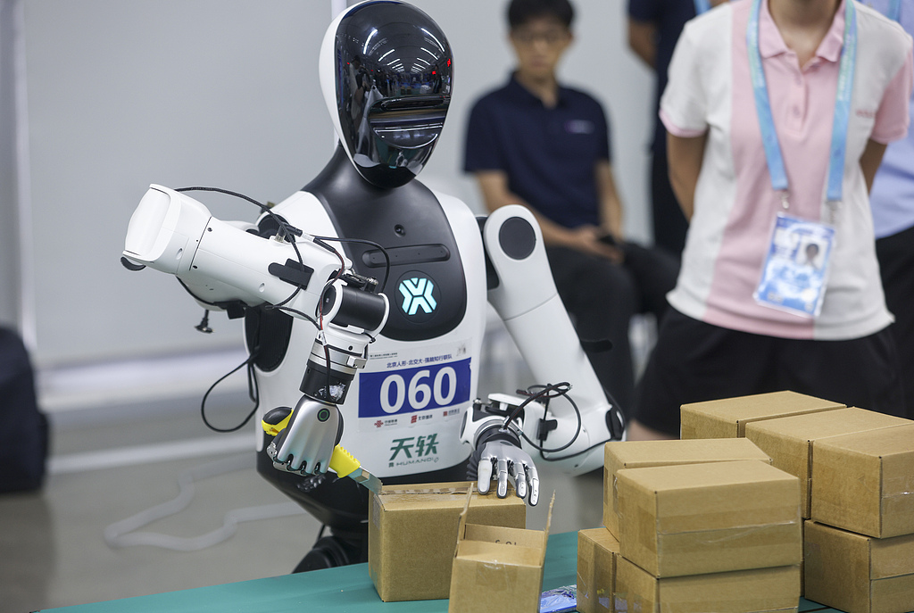 Un concurrent de robot effectue une tâche de déballage lors de la compétition de main adroite lors des deuxièmes Jeux mondiaux du robot humanoïde à Pékin le 17 août 2026. /VCG