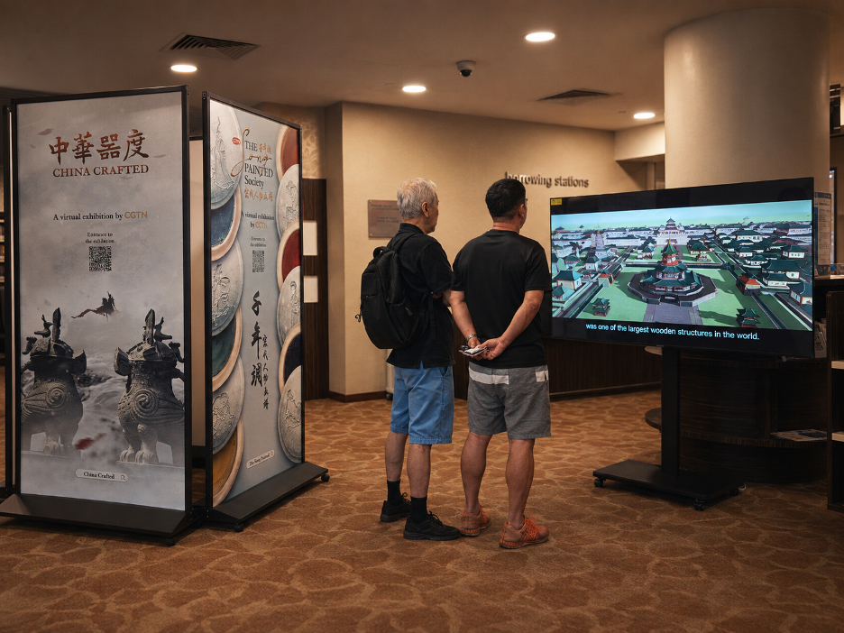 Les visiteurs s'arrêtent pour regarder un film China Crafted à la bibliothèque Chinatown de Singapour. /CGTN