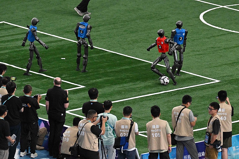 Un robot humanoïde dribble devant un défenseur lors du grand match de football robotisé des 2e Jeux mondiaux du robot humanoïde au National Speed ​​Skating Oval de Pékin, en Chine, le 26 août 2026. /VCG 