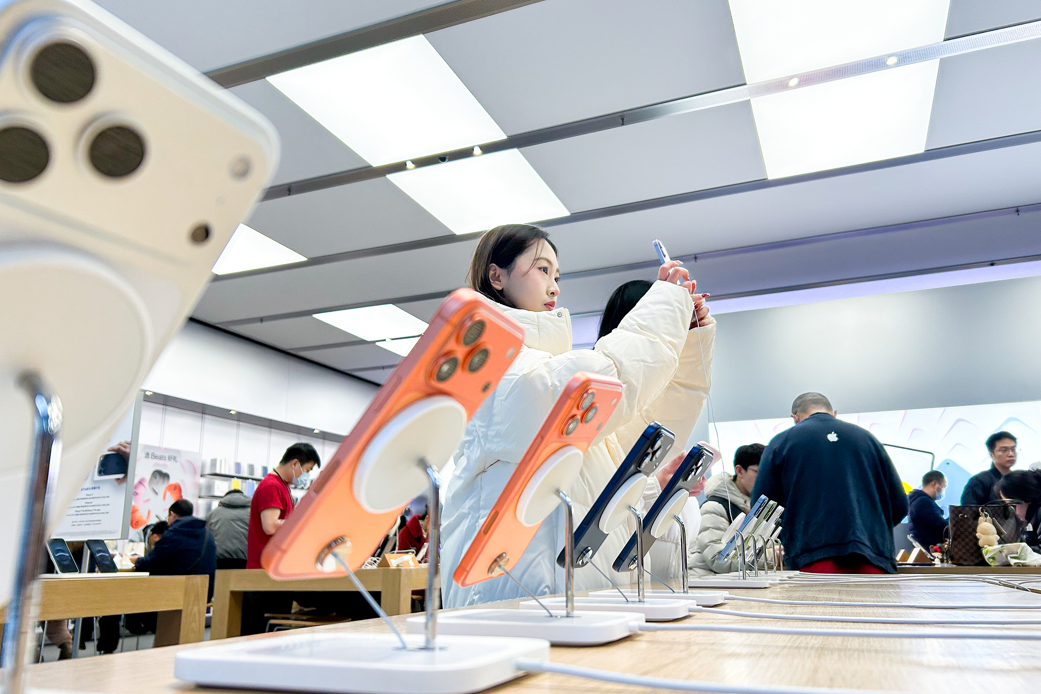 Des gens essaient des smartphones dans un Apple Store à Chengdu, dans la province du Sichuan, dans le cadre du programme chinois d'échange d'achats de téléphones portables par les consommateurs, le 2 janvier 2026. /VCG