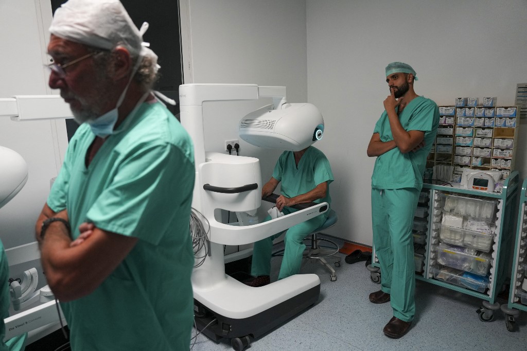 Sasha Stamenkovic (au centre) utilise le nouveau système chirurgical assisté par robot Da Vinci 5 lors d'une intervention chirurgicale contre le cancer du poumon sous le regard d'Ali Ansaripour (à droite), stagiaire cardiothoracique senior dans le cadre d'une bourse de recherche en robotique. /Carlos Jasso/AFP