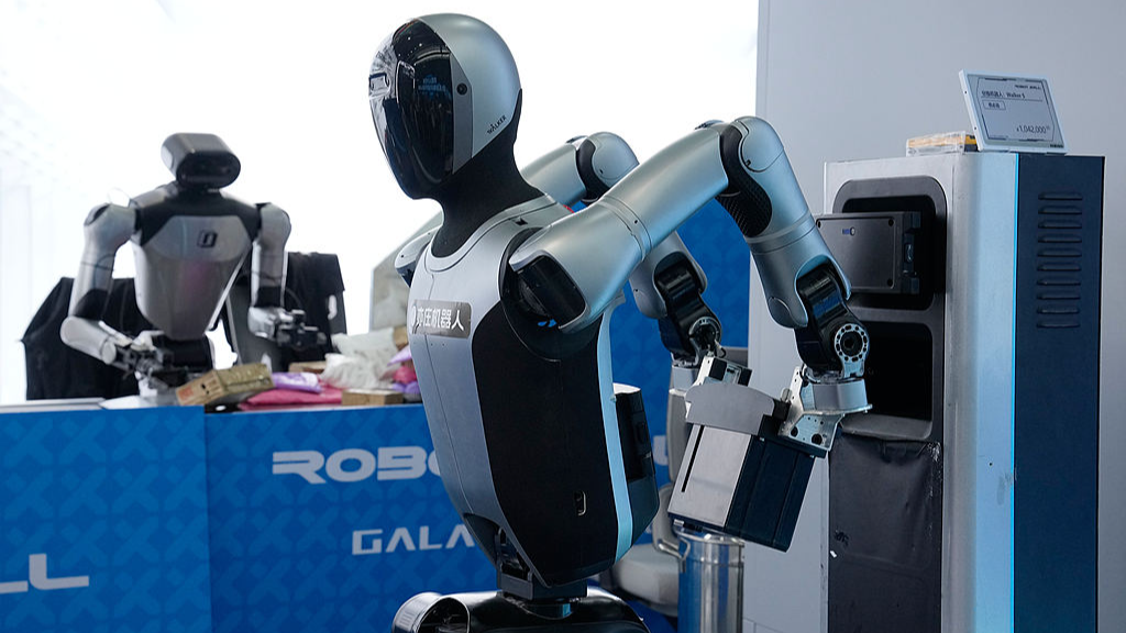 Au premier plan, un robot remplace sa propre batterie tandis qu'un autre trie des colis en arrière-plan au Centre d'innovation en robotique humanoïde de Pékin, dans la ville électronique de Pékin (Yizhuang), en Chine, le 29 mai 2026. /VCG