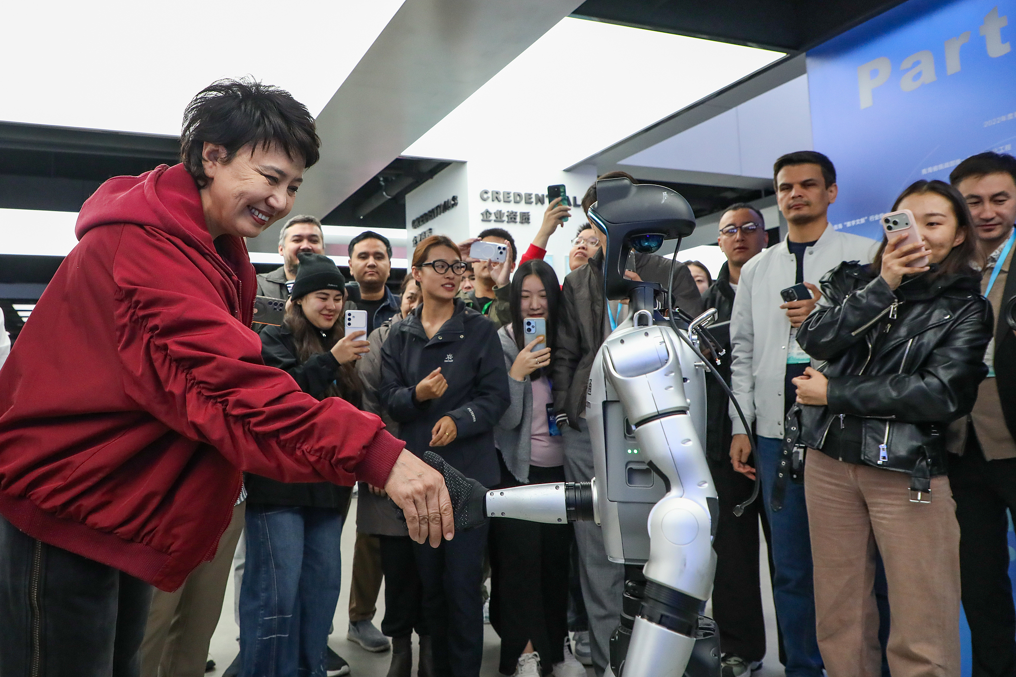Un visiteur serre la main d'un robot humanoïde au parc de démonstration de l'énergie verte et de l'intégration du calcul intelligent de Sanjiangyuan de China Unicom, Xining, province du Qinghai, Chine, le 19 septembre 2026./ VCG