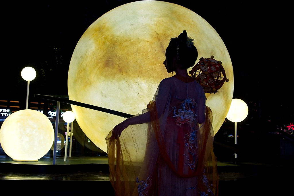 Une femme en costume traditionnel pose devant une installation artistique sur la lune sur Nanjing East Road à Shanghai, dans l'est de la Chine, le 26 septembre 2026. /VCG