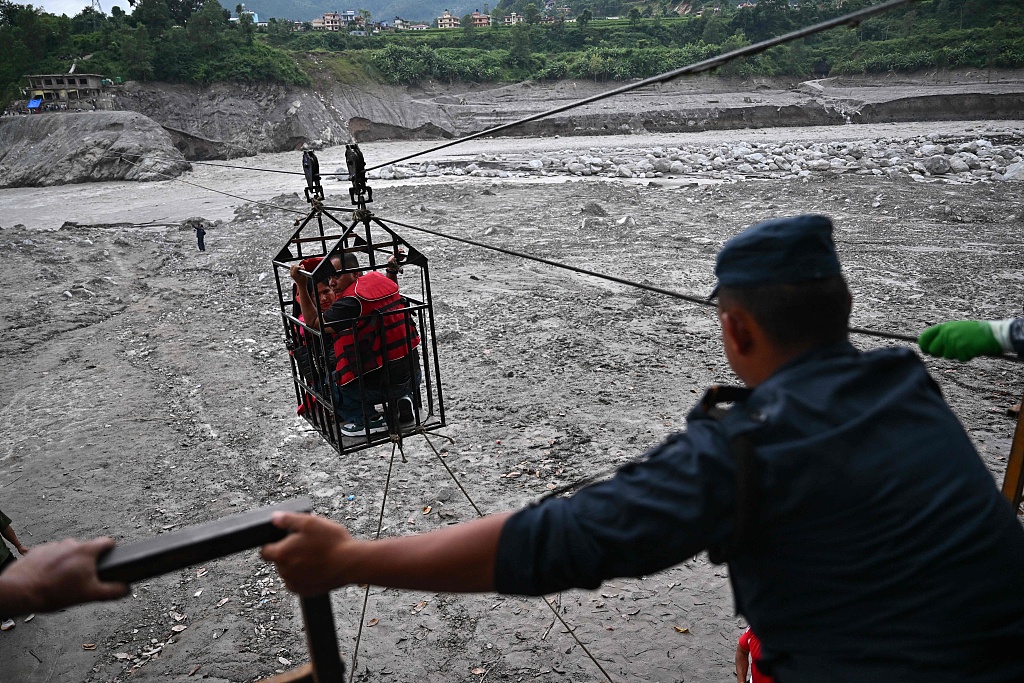 Des gens traversent la rivière Trishuli via une tyrolienne installée à la suite d'inondations soudaines au centre Trishuli, dans le district de Nuwakot au Népal, le 4 septembre 2026. /VCG