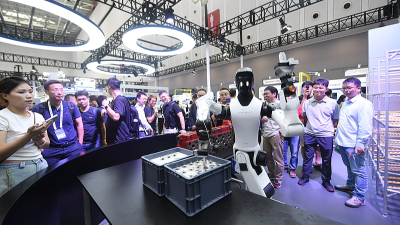 Des visiteurs regardent un robot humanoïde démontrer l'assemblage d'un moteur lors de la conférence Yunqi 2026 à Hangzhou le 22 septembre 2026. /VCG