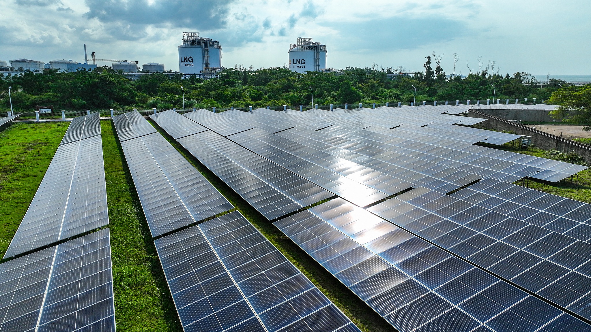 Panneaux solaires au premier plan d'une vue du dépôt de stockage de GNL de la société PetroChina Natural Gas Sales Hainan dans la zone de développement de Laocheng à Chengmai, province de Hainan, Chine, le 16 septembre 2026. /VCG