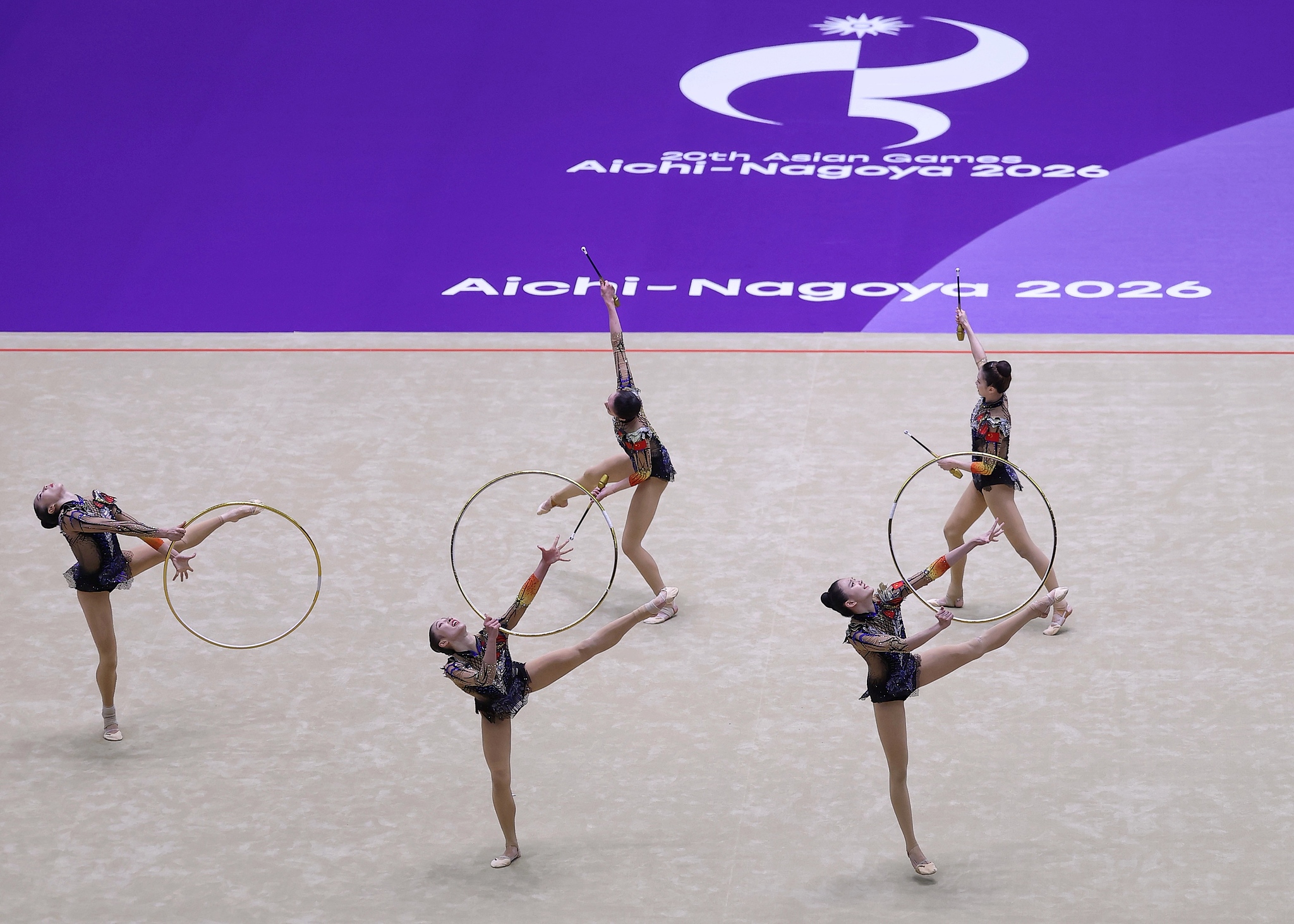Les Chinois Xinyi Ding, Miaoting Liu, Yanzhu Pu, Lanjing Wang et Xinyi Zhang participent à l'épreuve des trois cerceaux et des deux massues aux Jeux asiatiques de 2026 à Nagoya, au Japon, le 3 octobre 2026. /VCG