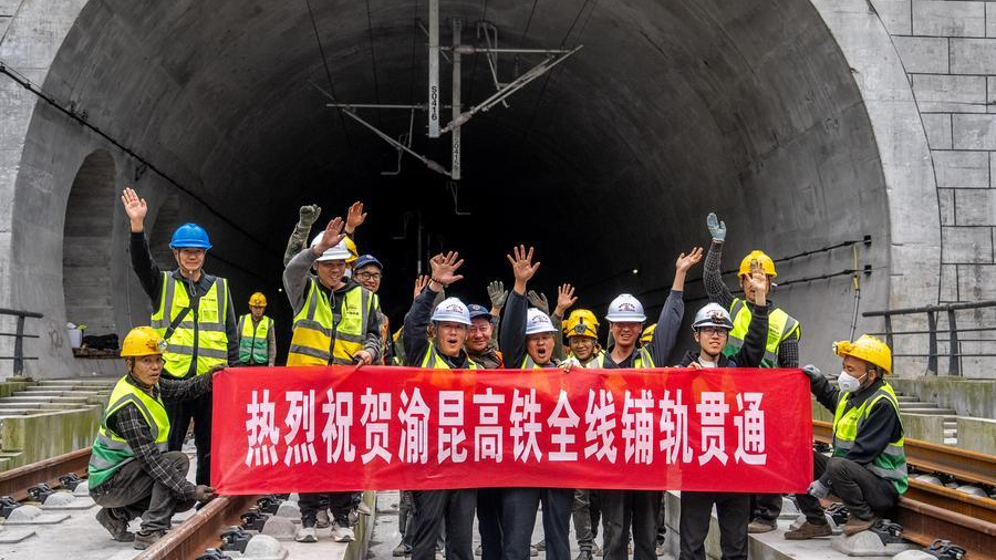 Des ouvriers posent pour des photos pour célébrer l'achèvement de la pose des voies du tunnel Junlian de la ligne à grande vitesse Chongqing-Kunming, à la frontière entre les provinces du Yunnan et du Sichuan, dans le sud-ouest de la Chine, le 24 octobre 2026. /Xinhua